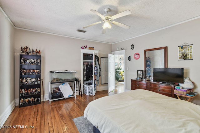 bedroom with a textured ceiling, ornamental molding, wood finished floors, and visible vents