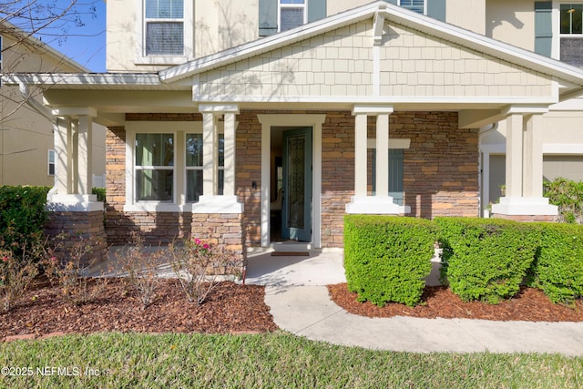 doorway to property featuring a porch and stone siding