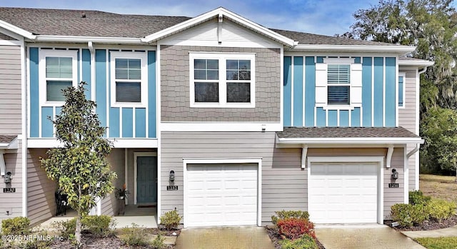 view of property featuring a garage, a shingled roof, and driveway