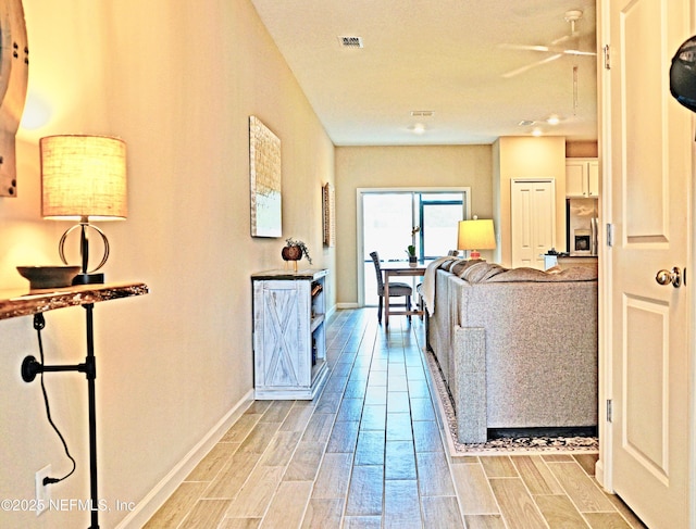 hallway featuring baseboards, visible vents, and wood tiled floor