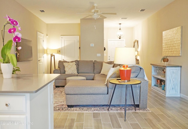 living area featuring a ceiling fan, visible vents, and wood tiled floor