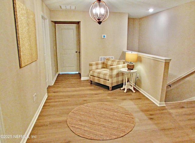 living area featuring baseboards, visible vents, an upstairs landing, and wood finished floors