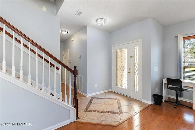 foyer with visible vents, stairs, baseboards, and wood finished floors