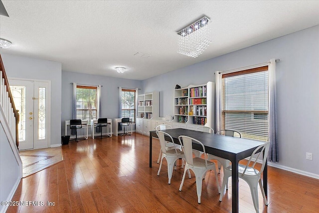 dining area featuring baseboards, wood-type flooring, and a textured ceiling