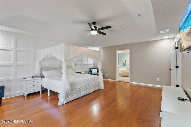 bedroom featuring visible vents, ceiling fan, baseboards, light wood-style floors, and a textured ceiling