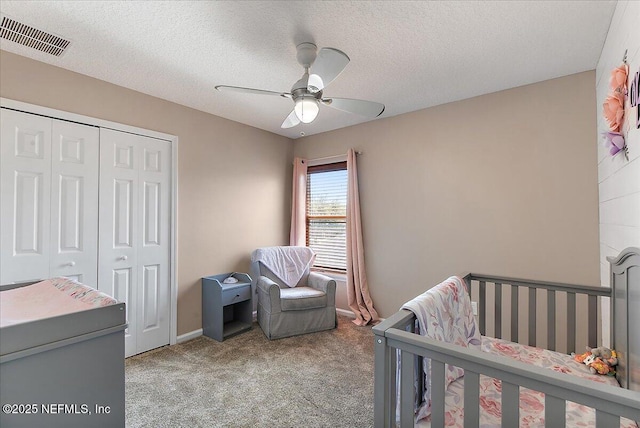 carpeted bedroom with a ceiling fan, baseboards, visible vents, a closet, and a textured ceiling