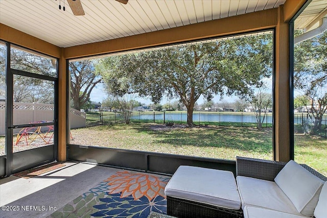 unfurnished sunroom with plenty of natural light, a ceiling fan, and a water view