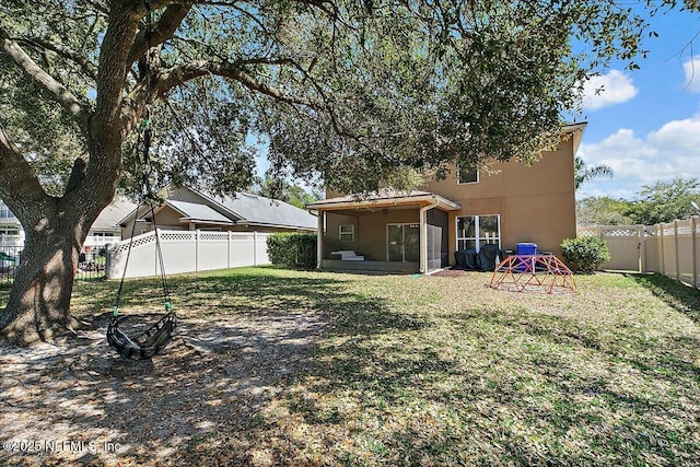 rear view of property with a fenced backyard, a lawn, a sunroom, and stucco siding