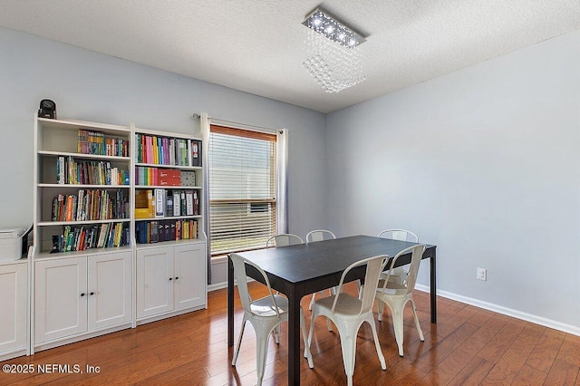 dining area with baseboards, a textured ceiling, and hardwood / wood-style floors