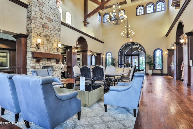 living area with a wealth of natural light, an inviting chandelier, a fireplace, and hardwood / wood-style flooring