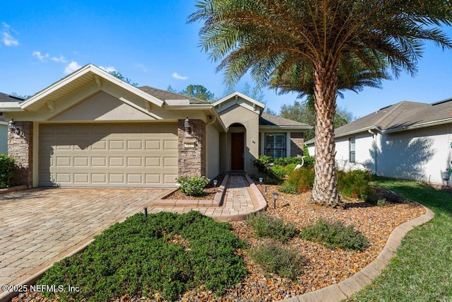 ranch-style home with stone siding, stucco siding, decorative driveway, and a garage