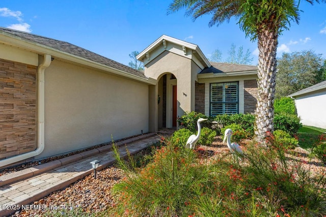 view of exterior entry featuring stucco siding and stone siding