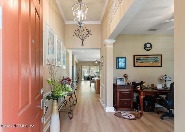 foyer featuring visible vents, crown molding, a chandelier, decorative columns, and light wood-style flooring