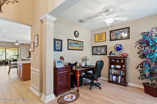 home office with visible vents, baseboards, light wood-style flooring, a ceiling fan, and ornate columns