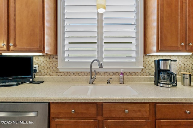 kitchen featuring decorative backsplash, brown cabinets, light countertops, and a sink