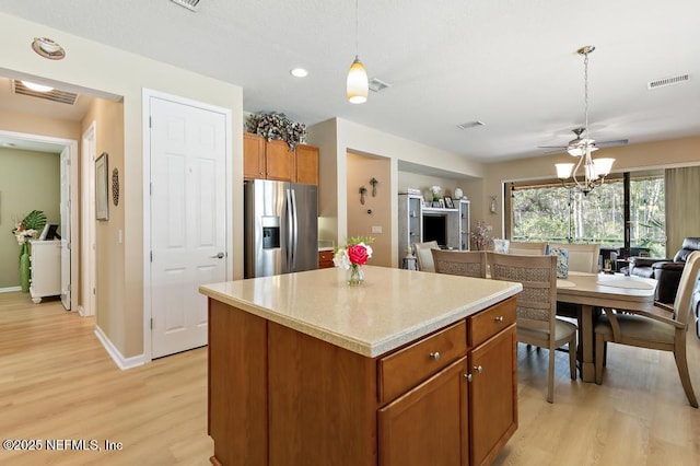 kitchen with open floor plan, visible vents, stainless steel refrigerator with ice dispenser, and a kitchen island