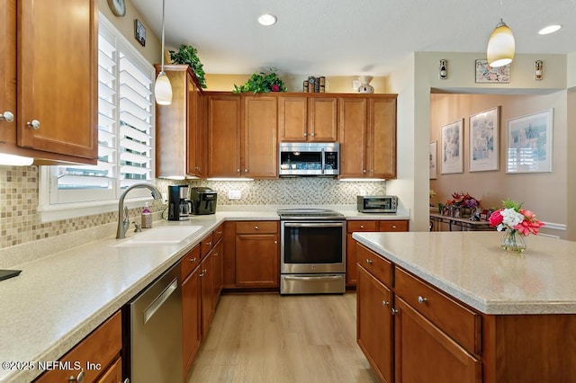 kitchen with a sink, light countertops, brown cabinetry, and stainless steel appliances