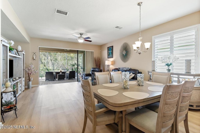 dining room with visible vents, ceiling fan with notable chandelier, baseboards, and light wood finished floors