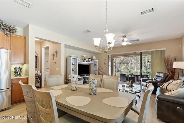 dining room featuring ceiling fan with notable chandelier, visible vents, and light wood-type flooring