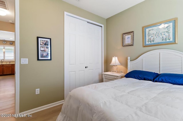 bedroom with a closet, baseboards, visible vents, and light wood-style flooring