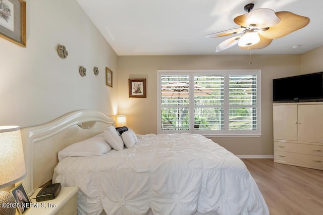 bedroom with light wood finished floors, baseboards, and ceiling fan