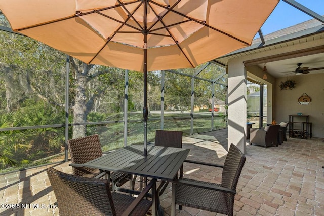 view of patio with a lanai, outdoor dining area, and a ceiling fan