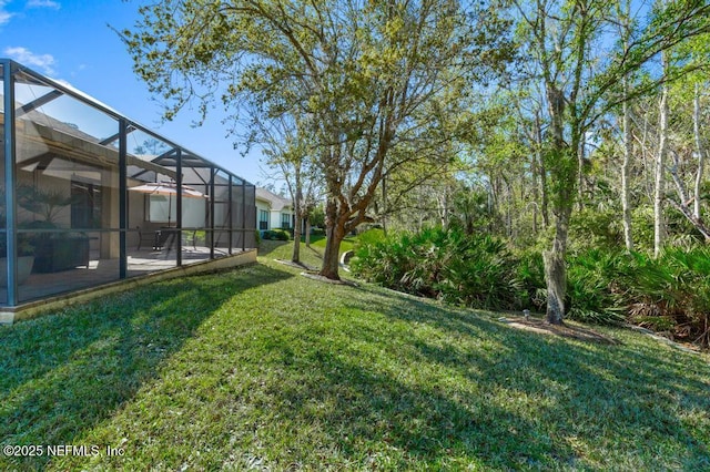 view of yard featuring glass enclosure and a patio