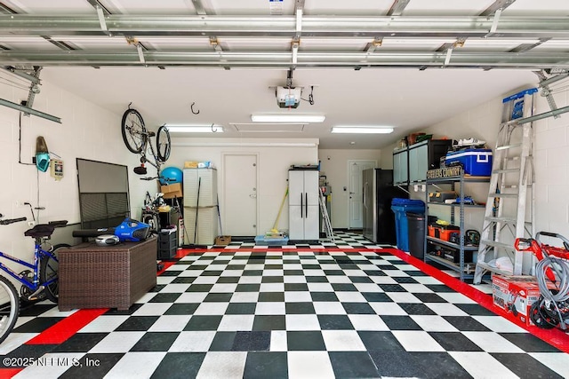 garage with a garage door opener, concrete block wall, and freestanding refrigerator