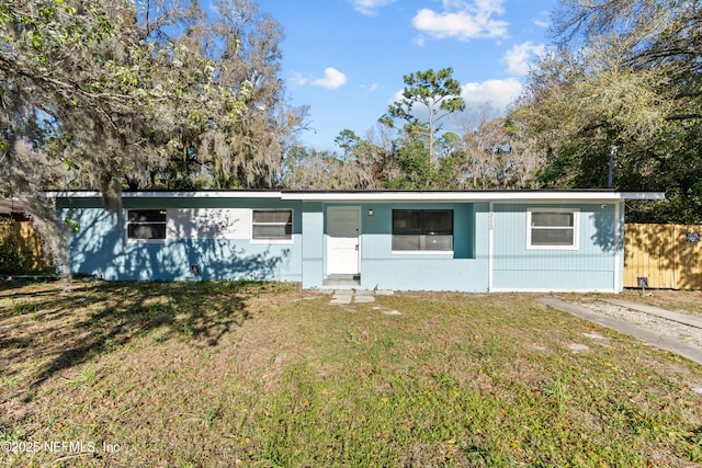 single story home with a front yard, concrete block siding, and fence