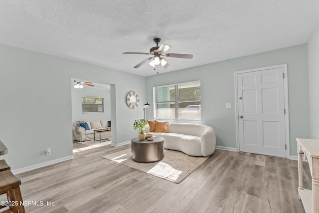 living room with light wood-type flooring, baseboards, and a textured ceiling