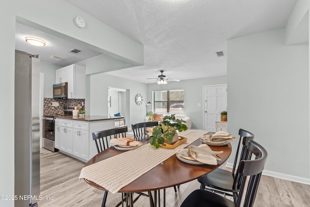 dining room featuring visible vents, light wood-style flooring, ceiling fan, a textured ceiling, and baseboards