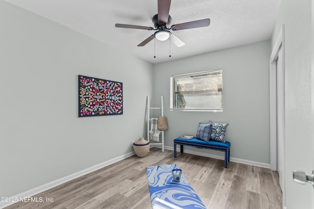 sitting room with a textured ceiling, wood finished floors, a ceiling fan, and baseboards