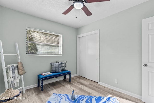 living area with ceiling fan, baseboards, and wood finished floors