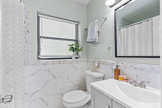 full bath featuring a healthy amount of sunlight, toilet, tile walls, and vanity