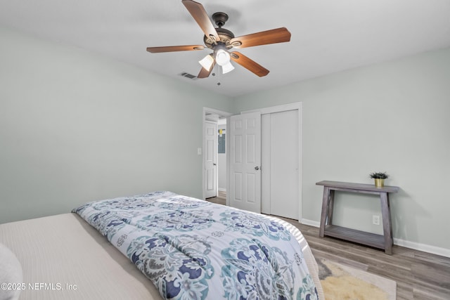 bedroom featuring a closet, visible vents, ceiling fan, wood finished floors, and baseboards