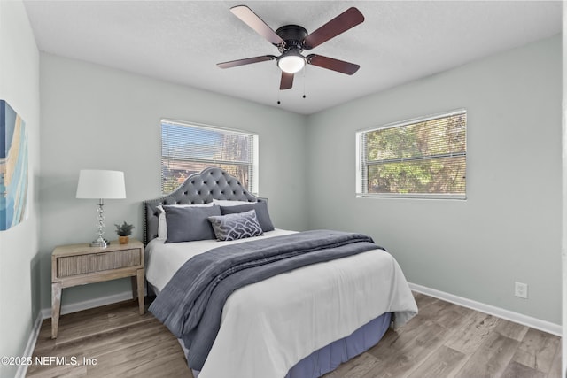 bedroom featuring wood finished floors, a ceiling fan, and baseboards