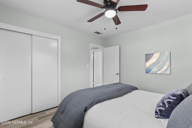 bedroom featuring a ceiling fan, a closet, visible vents, and wood finished floors