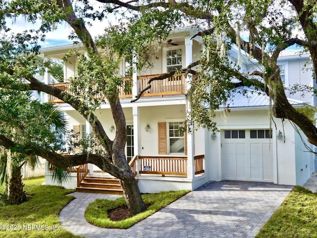 view of front of house featuring decorative driveway, a balcony, a porch, and stucco siding