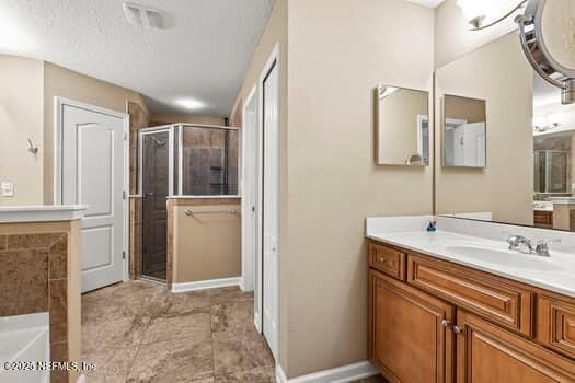 bathroom with a stall shower, a garden tub, vanity, and baseboards