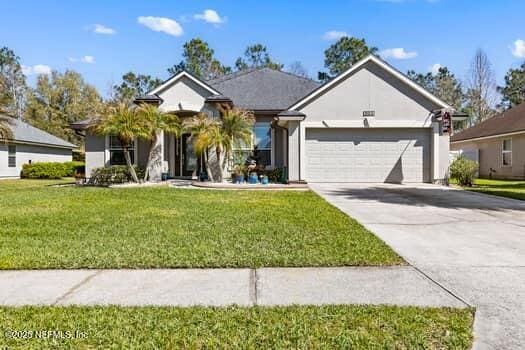 single story home with driveway, an attached garage, and a front yard