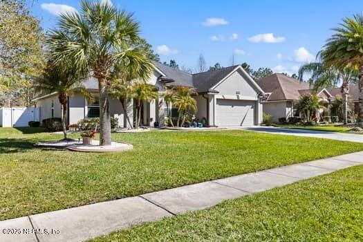 view of front facade with a front yard, driveway, a residential view, and an attached garage