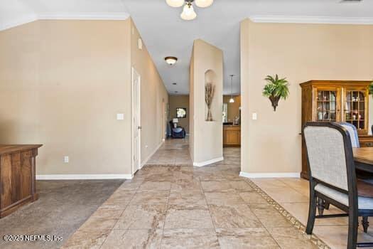 foyer entrance with crown molding, lofted ceiling, and baseboards