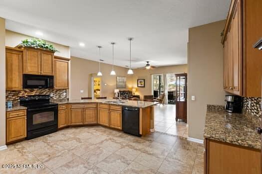 kitchen with a peninsula, black appliances, tasteful backsplash, and brown cabinets