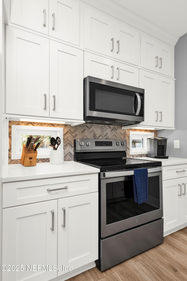 1306 1st St S, Jacksonville Beach, FL 32250 - kitchen with light wood finished floors, white cabinetry, appliances with stainless steel finishes, and light countertops