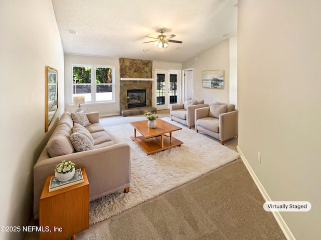 living room with baseboards, carpet, vaulted ceiling, a textured ceiling, and a fireplace