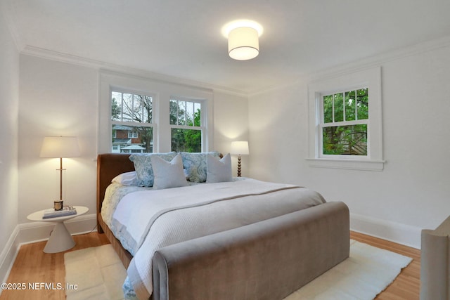 bedroom with ornamental molding, baseboards, and wood finished floors