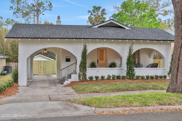 view of front of home with covered porch, a shingled roof, a chimney, and brick siding