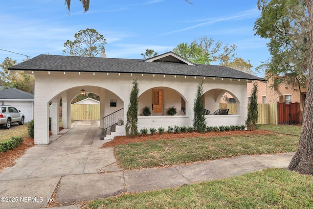 view of front of property with covered porch, brick siding, roof with shingles, and fence