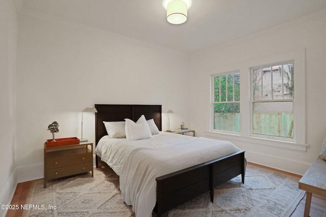 bedroom featuring ornamental molding, wood finished floors, and baseboards