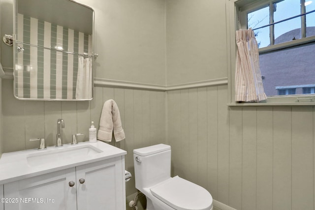 bathroom featuring toilet, wainscoting, and vanity